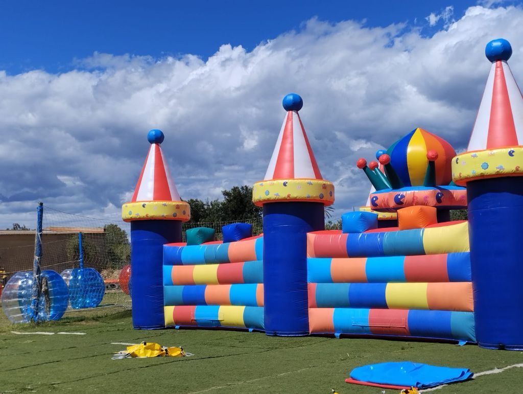 Colorful outdoor inflatable castle with blue and red towers and zorbing balls