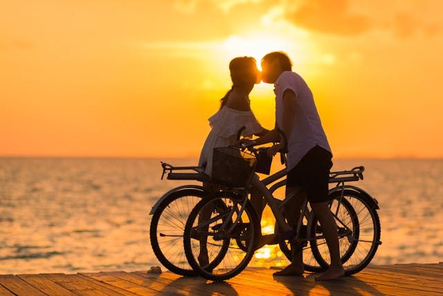 Silhouette of couple kissing at sunset with bicycles
