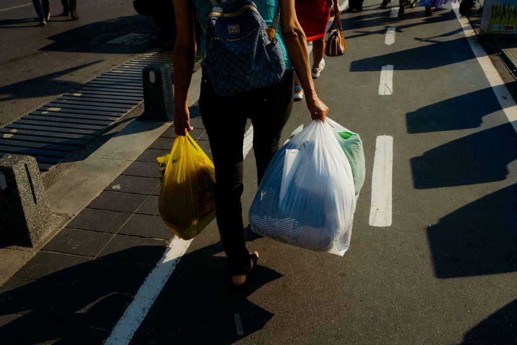 Person carrying plastic bags highlighting the need for alternatives